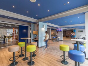 A modern interior with high ceilings, recessed lighting, and a mix of seating options including stools and tables. - ibis budget Curitiba Centro (Curitiba)