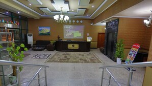 A hotel lobby with a reception desk, a map on the wall, a chandelier, and a staircase. - Asia Grand Hotel (Dushanbe)