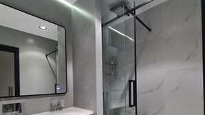A modern bathroom with a glass-enclosed shower, a large mirror, and a white vanity with a towel. - Asia Grand Hotel (Dushanbe)