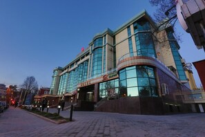 A hotel with a modern glass facade, a prominent entrance, and a visible staircase leading to the lobby. - Asia Grand Hotel (Dushanbe)