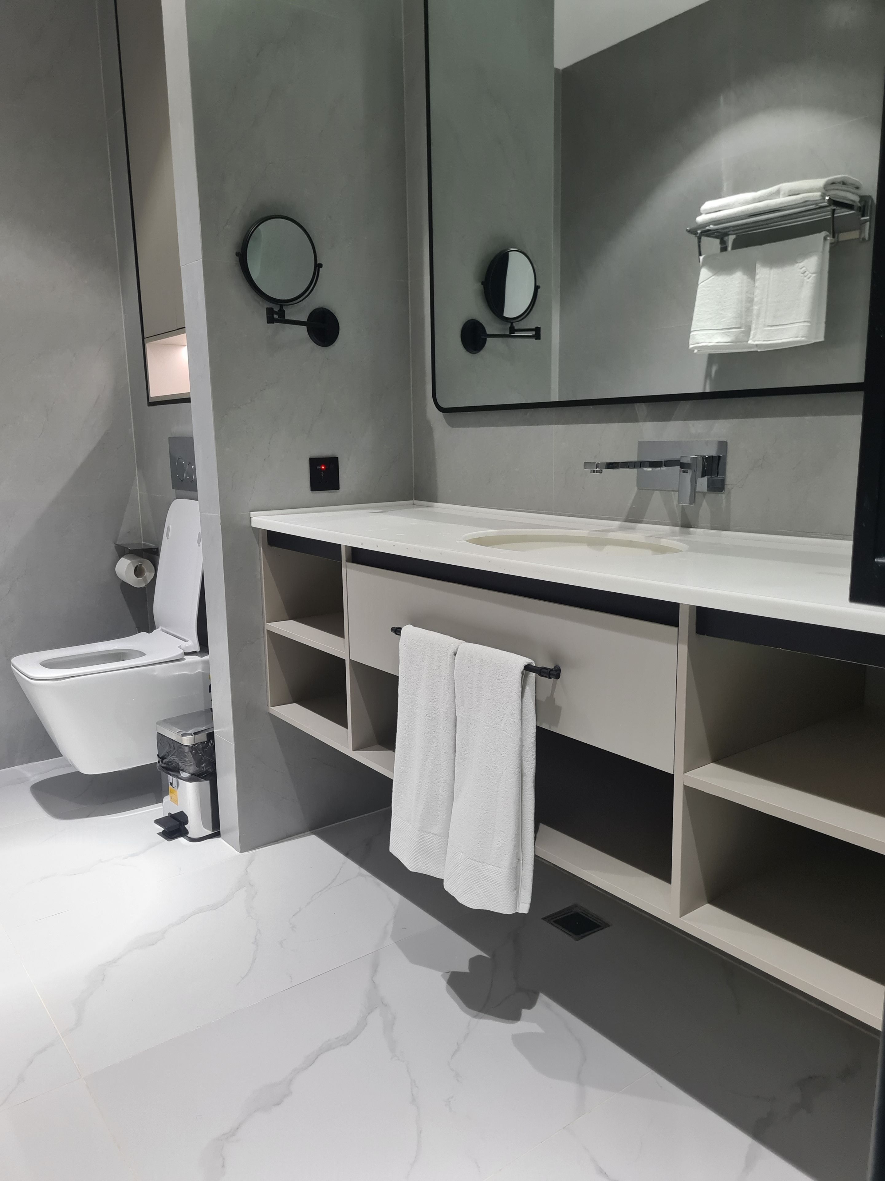 A modern bathroom with a toilet, sink, and mirror.