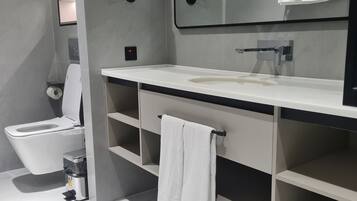 A modern bathroom with a toilet, sink, and mirror.