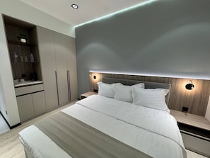 A modern bedroom with a large bed, built-in wardrobe, bedside tables, and wall-mounted lighting. - Asia Grand Hotel (Dushanbe)