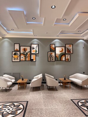 Un espace d’attente moderne agrémenté d’un décor au plafond, d’œuvres d’art murales, de sièges et d’un motif décoratif sur le sol.
