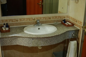 Une salle de bain équipée d’un lavabo, d’un miroir et d’articles de toilette.