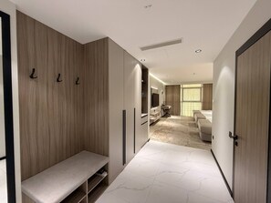 Habitación de hotel moderna con vestidor, un banco, un escritorio, una cama y un ventanal grande.