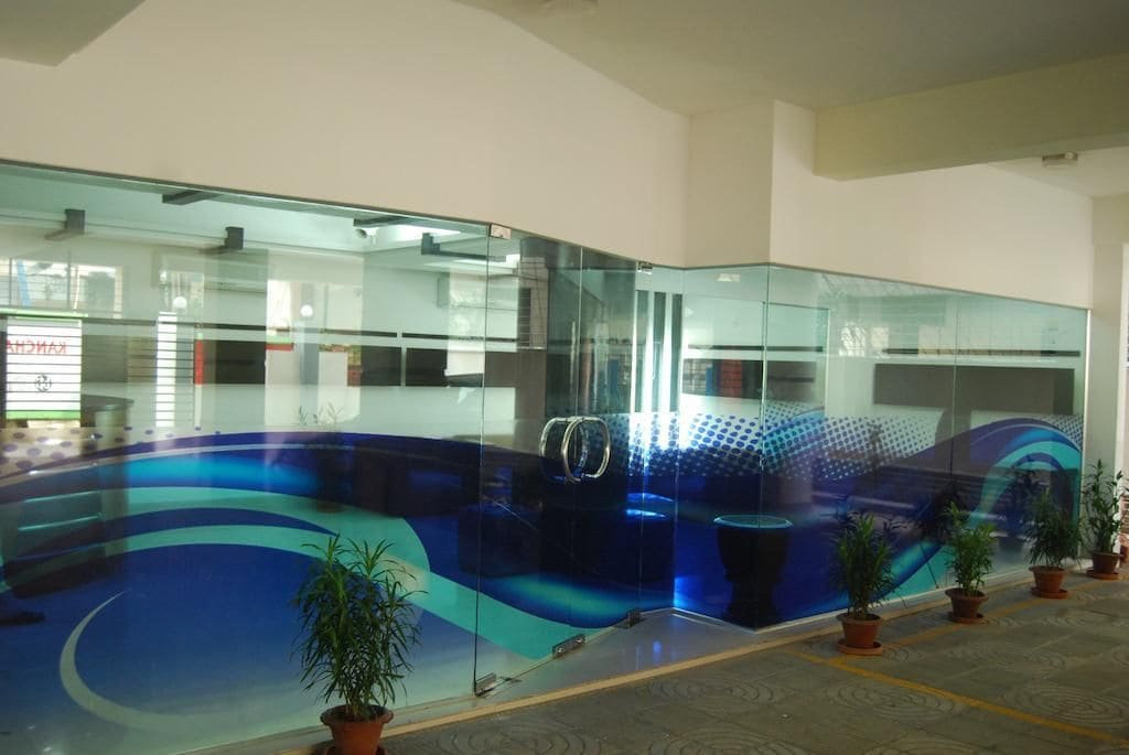 A modern interior with glass partitions, potted plants, and a blue patterned floor.
