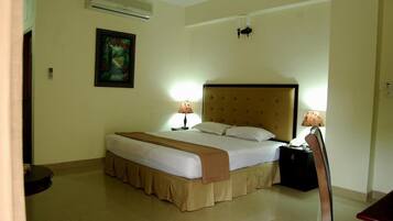 A hotel room with a bed, bedside lamps, a nightstand, and a painting on the wall.