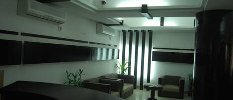 Un interior moderno con una mesa de recepción, zona de estar y unidades de aire acondicionado.