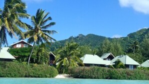A coastal resort with bungalow-style accommodations, a clear turquoise sea, and lush greenery. - Sokala Villas (Rarotonga)