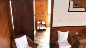 A wooden interior with wicker chairs and a stone floor. - Sokala Villas (Rarotonga)
