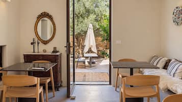 Un espacio habitable de concepto abierto con comedor, un conjunto de sofás y vista a un jardín exterior a través de una puerta de vidrio.