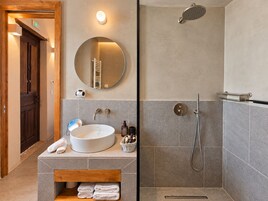Un baño con un espejo redondo, un lavabo, una ducha y un perchero para toallas.