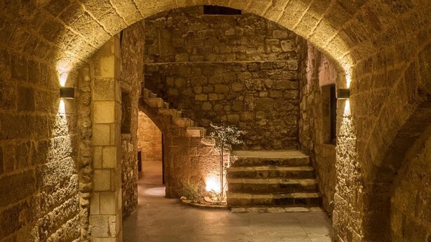 Un couloir aux murs de pierre, avec un escalier menant à un niveau supérieur.