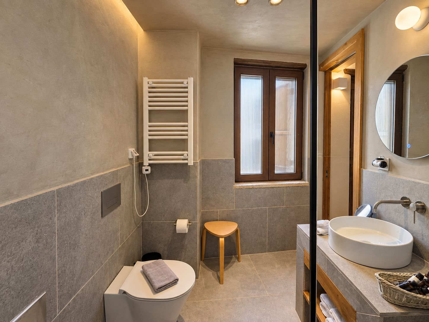 Ein modernes Badezimmer mit Toilette, Waschbecken, Spiegel und Handtuchhalter.