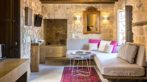 Une pièce chaleureuse avec un mur en pierre, un plafond en bois, un canapé, une petite table et un miroir.