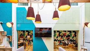 A modern lounge area with wooden furniture, a flat-screen TV, and colorful wall art. - Ibis Styles Parc des Expositions de Villepinte (Villepinte)