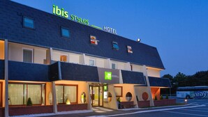 Un hôtel appelé « ibis Styles Hotel », doté d’un design moderne, de grandes fenêtres et d’un espace de stationnement.