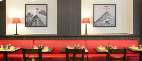 A restaurant with red booths, wooden tables, and pendant lighting.