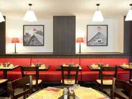 Un restaurante con asientos de tapicería roja, mesas de madera e iluminación colgante.