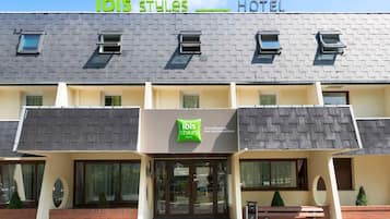 A hotel named "ibis Styles" with a modern design, featuring a flat roof, large windows, and a welcoming entrance.