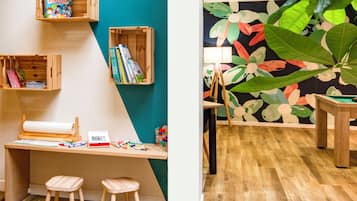 A room with a wooden desk, stools, and shelves with books and toys.