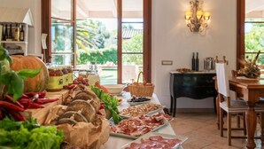 A buffet table with various food items, a pumpkin, and a view of the outdoors through large windows. - Agriturismo Villa Toscana (Campiglia Marittima)