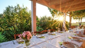 An outdoor dining area with tables set for a meal, surrounded by greenery and a clear sky. - Agriturismo Villa Toscana (Campiglia Marittima)