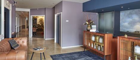 Een moderne woonkamer met een leren bank, een glazen salontafel en een houten kast met glazen deuren.