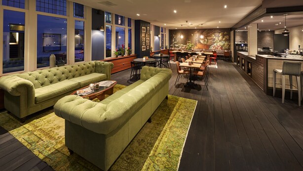 A modern interior with a green sofa set, dining area, and kitchen. - Hotel Lion d'Or (Haarlem)