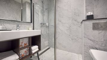 Une salle de bain moderne avec une douche à parois de verre, un lavabo blanc et des toilettes.