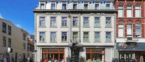 A multi-story building with 'HOTEL LION D'OR' signage, a cafe, and a restaurant named 'Raja Thai' on the ground floor.