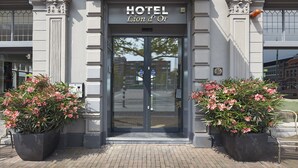 The entrance to a hotel with a large glass door, two potted plants, and a sign above the door that reads "HOTEL Lion d'Or". - Hotel Lion d'Or (Haarlem)