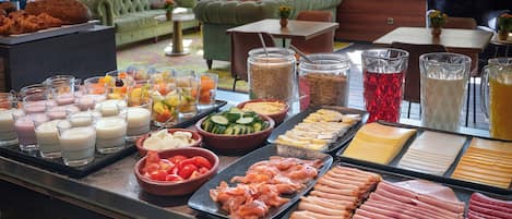 Ein Buffet mit verschiedenen Speisen, darunter Fleisch, Käse und Obst.