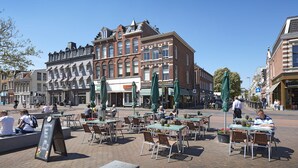 An outdoor café with tables and chairs, surrounded by historic buildings. - Hotel Lion d'Or (Haarlem)