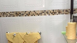 A bathroom with a white sink, a yellow towel with floral embroidery, and a tiled backsplash. - Ocho Rios Golden View (Kingston)
