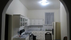A compact kitchen with white cabinets, a gas stove, a sink, and a refrigerator. - Ocho Rios Golden View (Kingston)