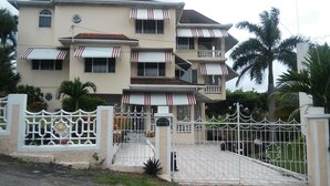 A multi-story house with a gated entrance, a balcony on the upper floor, and a small garden area. - Ocho Rios Golden View (Kingston)