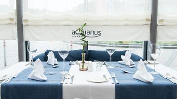 A table set for two with a blue tablecloth, white napkins, and a vase with a green plant.
