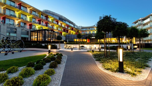 Un hotel moderno con un patio central, varios balcones y una entrada bien iluminada.