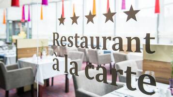 A restaurant interior with tables and chairs, a glass wall, and hanging decorations.