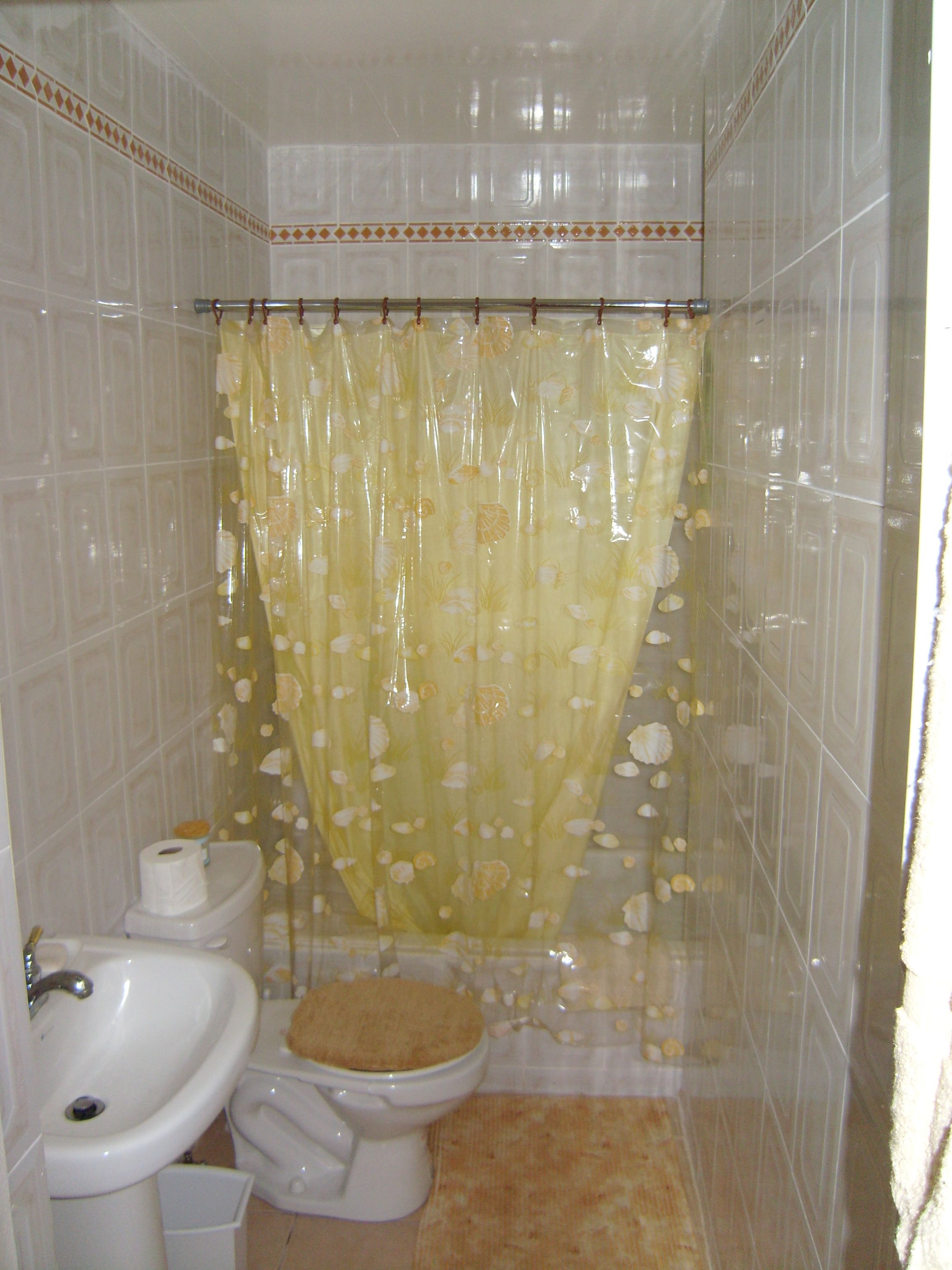 Un baño con inodoro, lavamanos y cortina de ducha.