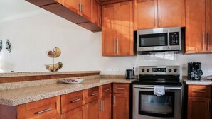 A kitchen with wooden cabinets, a stainless steel microwave, an oven, and a granite countertop.