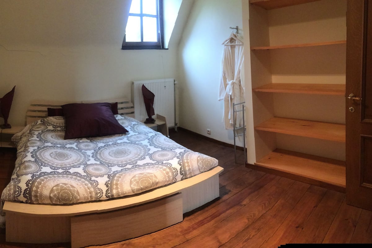 A bedroom with a bed, a radiator, a window, and a wooden floor.