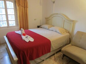 A bed with a red blanket, a white pillow, and a towel with a red flower.