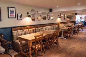 Un restaurante con una amplia zona de asientos con banco de madera, mesas y sillas de madera.