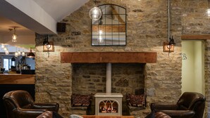 Una sala de estar acogedora con chimenea de piedra, sofás de cuero y vigas de madera a la vista.