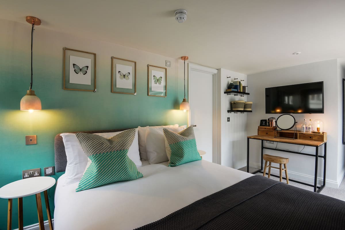 A modern bedroom with a bed, bedside tables, a desk, and a television.