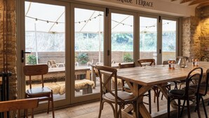 Un comedor con una gran mesa de madera, sillas y vistas al exterior a través de puertas de vidrio amplias.