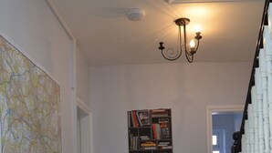 A hallway with a radiator, a map on the wall, a bookshelf, and a staircase.